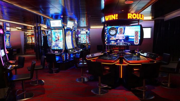 Casino floor filled with brightly lit slot machines and gaming tables, illustrating the windowless, clock-free environment of a casino.