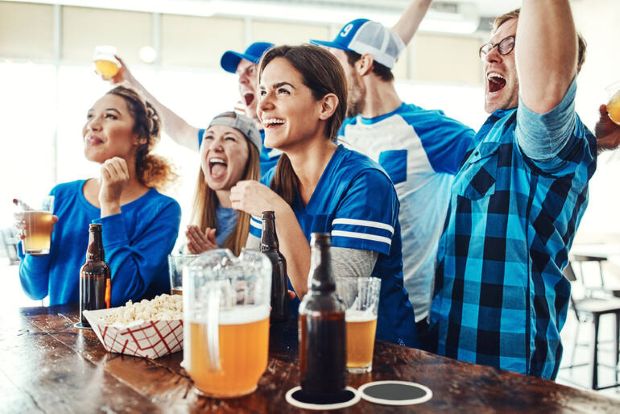 Friends cheering and drinking beer while watching the World Cup at a neighbourhood brewery.