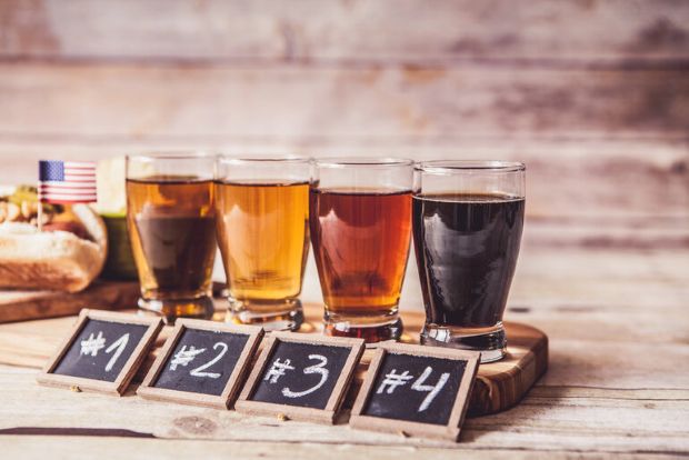 Craft beer flight featuring four glasses of beer in different colors, labeled from #1 to #4 on a wooden table.