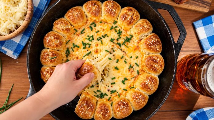 Oktoberfest beer cheese and pretzel skillet with melted cheese and chives.