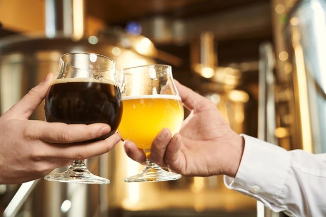 Two glasses of beer cheering at a brewery table, illustrating common financial blind spots that can impact brewery profitability and business growth.