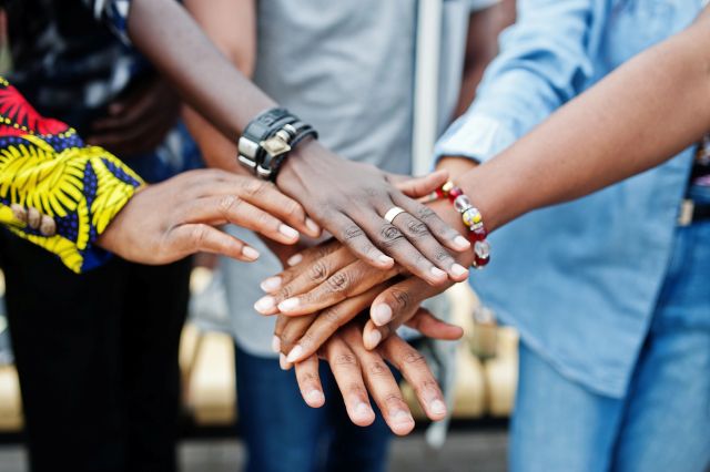 A group of diverse African people stacking their hands together in unity.